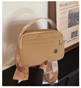 Detail of khaki nylon crossbody bag with silver zipper and adjustable wide shoulder strap