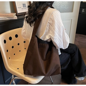 Dettaglio di una grande borsa tote in tela marrone scuro con ampia tracolla in stile OOTD