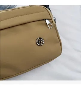 Vue détaillée du sac bandoulière en nylon kaki avec fermeture éclair et logo en métal