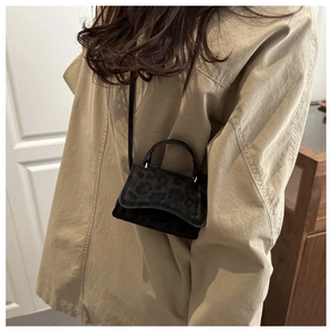 Close-up of a mini black suede crossbody bag with leopard texture on a fashion model