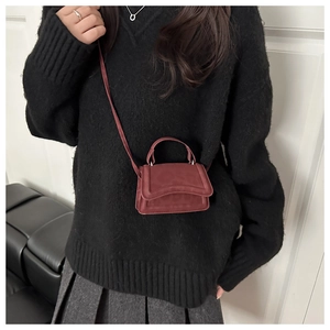 Close-up of a burgundy mini crossbody bag with matte suede texture and top handle