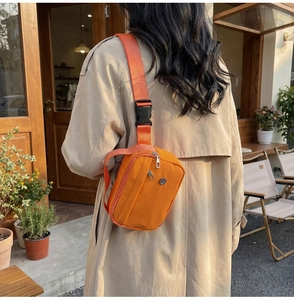 Gros plan d'un sac bandoulière en nylon orange vif avec double fermeture éclair