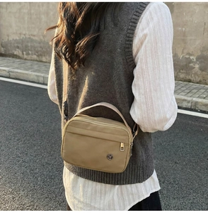 Vue de rue extérieure d'un sac bandoulière en nylon kaki porté avec une tenue décontractée