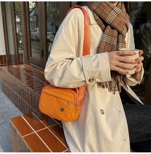 Détail de la sacoche en nylon orange vif avec poche zippée frontale et décor métallique