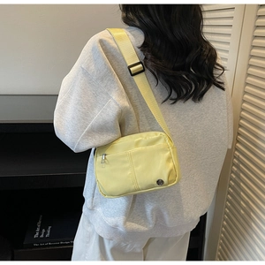 Lemon yellow nylon crossbody bag with adjustable wide strap shown in a lifestyle setting
