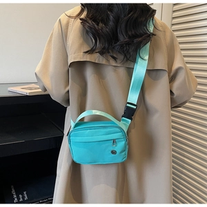 Mint green nylon crossbody bag featuring dual zippers and adjustable wide strap