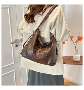 Detail view of large dark brown hobo bag with embossed logo on soft leather surface