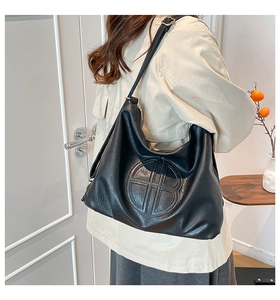 Detail of adjustable strap and embossed circular logo on black large hobo tote bag