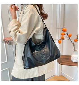 Detail showing the embossed circular logo on a minimalist black faux leather tote bag