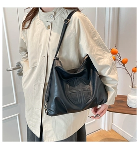 Detailed view of black faux leather large hobo bag with embossed round logo on the front