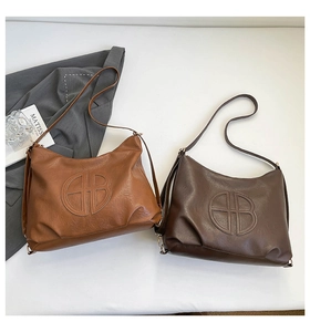 Detailed flat lay of brown and coffee large tote bags with embossed logo and leather texture
