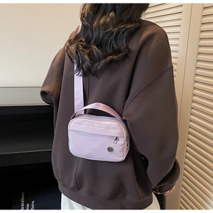 Detail of light purple nylon mini crossbody bag with adjustable shoulder strap and zip pocket