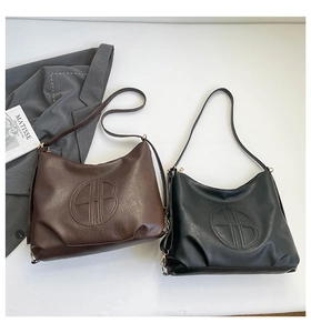 Detailed view of large leather tote bags with embossed logo in black and brown colors