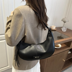 Chic black leather crescent hobo bag for women with tassel detail and metal plate