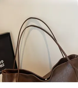 Close-up of slim double shoulder straps and fine stitching on brown retro tote bag