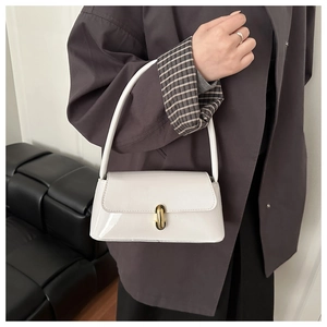Détail du sac baguette en cuir verni blanc avec une boucle en métal doré cylindrique