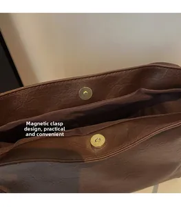 Detail view of the secure magnetic clasp on this vintage brown leather tote bag
