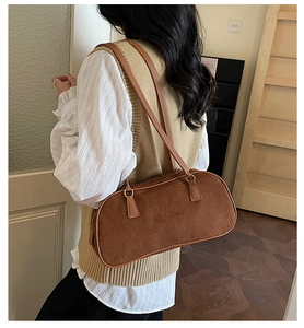 Detail of a brown vintage suede baguette bag with leather strap on a model's shoulder