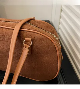 Detail of caramel faux suede handbag showing the durable zipper and leather strap connection