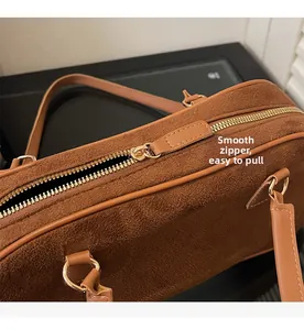 Detail shot of smooth gold-tone zipper on retro brown suede shoulder bag for women
