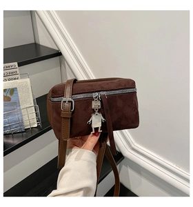 Detail of dark brown suede crossbody bag with silver robot charm and zipper closure