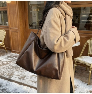 Detail of soft dark coffee PU leather tote bag worn by model in a winter outdoor setting