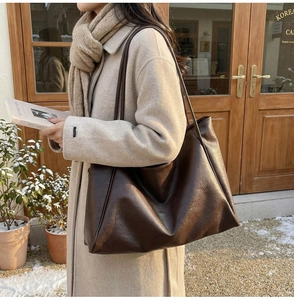Detail of a large dark brown PU leather tote bag styled with a winter wool coat