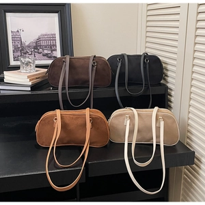 Detail of four faux suede rectangular shoulder bags in brown black and beige tones