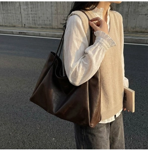 Detail of a large dark brown PU leather tote bag shown on a model for daily commute