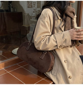 Close-up of a brown suede shoulder bag featuring a sleek retro baguette design
