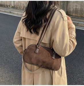 Close-up of retro brown suede shoulder bag worn with a classic trench coat in street style