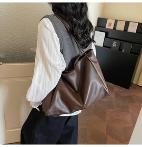 Rear view of a model carrying a vintage dark brown leather tote bag with large capacity