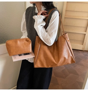 Brown vintage faux leather tote bag and pouch set worn by a model in a minimal setting