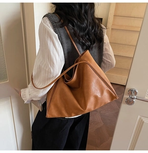 Detail of a large brown faux leather tote bag with stylish pleated texture for commuting