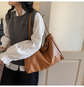 Detailed view of a brown vintage tote bag with leather texture worn by a model indoors