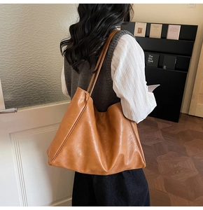 Detailed view of a brown minimalist PU leather tote bag worn by a model in a cozy library