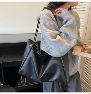 Close-up of black leather tote bag with subtle pleated texture and slender straps