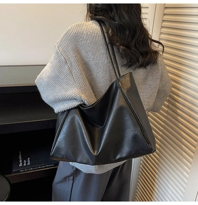 Detail of the textured black leather tote bag worn by model in minimalist setting