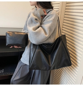 Detail of minimalist black leather tote bag set with matching pouch on model