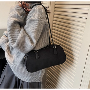 Detail of minimalist black suede baguette bag showing the slim strap and silver metal hardware