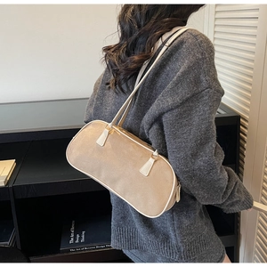Detail of khaki suede baguette bag with cream leather trim shown on shoulder