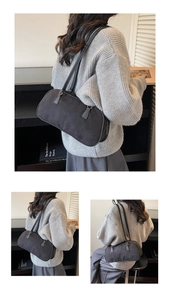 Detail of minimalist black suede shoulder bag with long leather handles and silver hardware