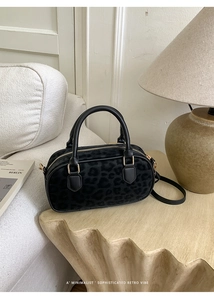 Close-up of leopard print bowling bag with gold hardware on a wooden table