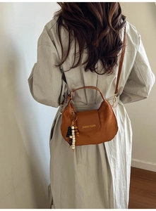 Detailed back view of a brown suede crescent bag featuring a stylish beaded charm accessory