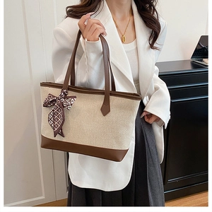 Détail du sac cabas en toile beige avec poignées en cuir marron et foulard décoratif
