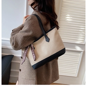 Detail view of large two-tone canvas tote bag with black leather straps and decorative scarf