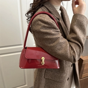 Sac baguette chic en cuir verni rouge avec boucle dorée porté par un mannequin