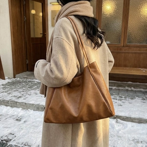 Classic large brown tote bag in pebbled leather shown on a model in a winter street scene