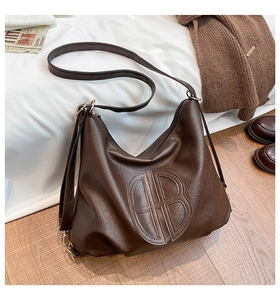 Macro detail of the dark brown lychee texture and embossed logo on this hobo shoulder bag