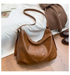 Detail of a brown textured faux leather hobo bag with an embossed round B logo detail